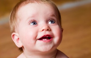 Amused baby boy (9-12 months) smiling, posing in studio, close-up, portrait