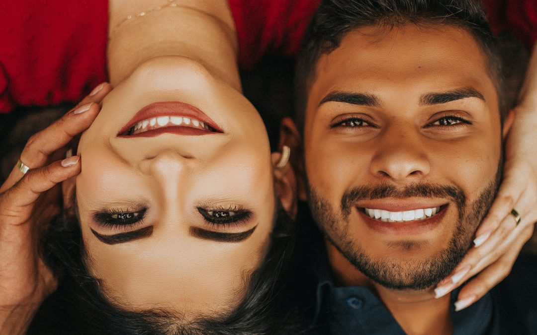 A man and woman smile with healthy teeth because they know how to floss properly
